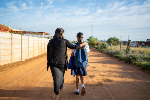Madre acompaña niña por un camino