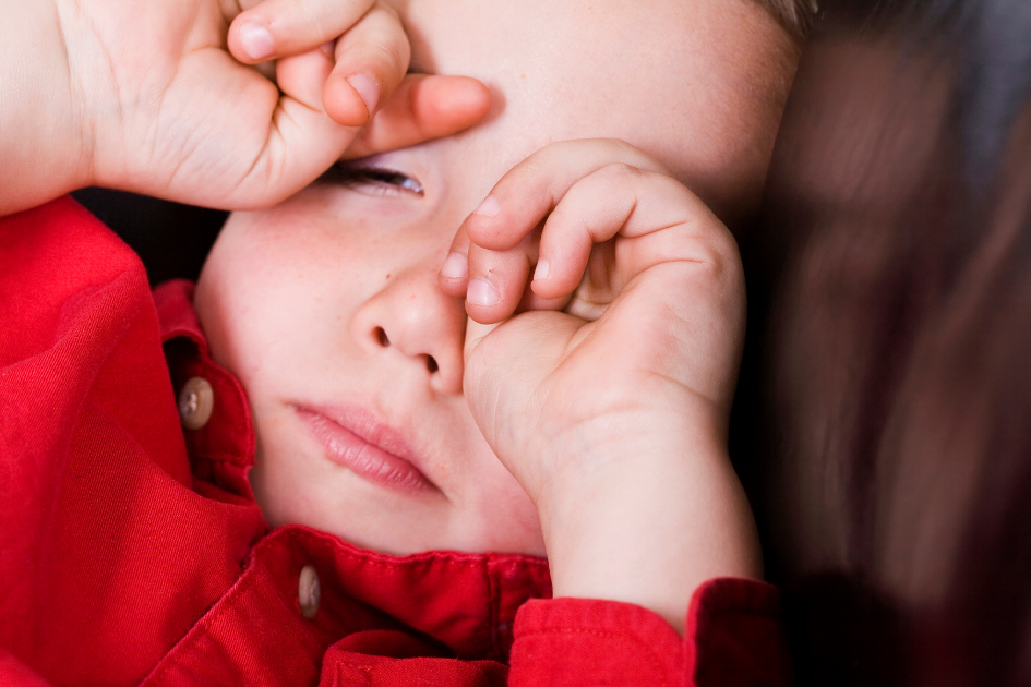 bebé con sueño frotándose los ojos