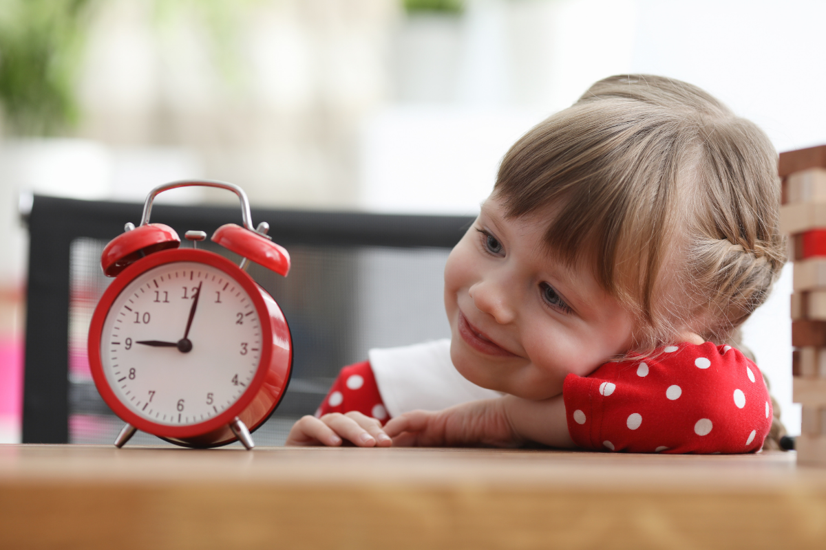 Niña vestida de rojo mirando un reloj de campana rojo