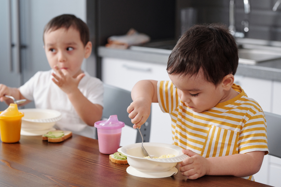 Niños pequeños comiendo solitos