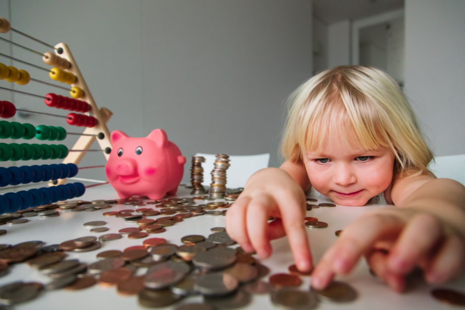 Un niño jugando con monedas y una hucha de cerdito