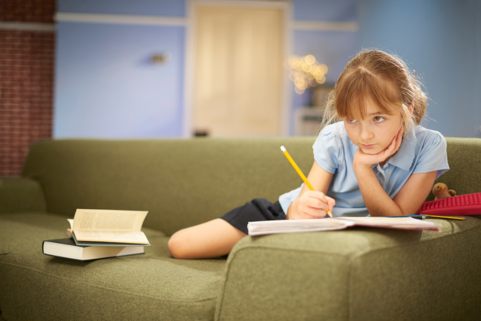 niña estudiando en el sofá mirando desconcentrada
