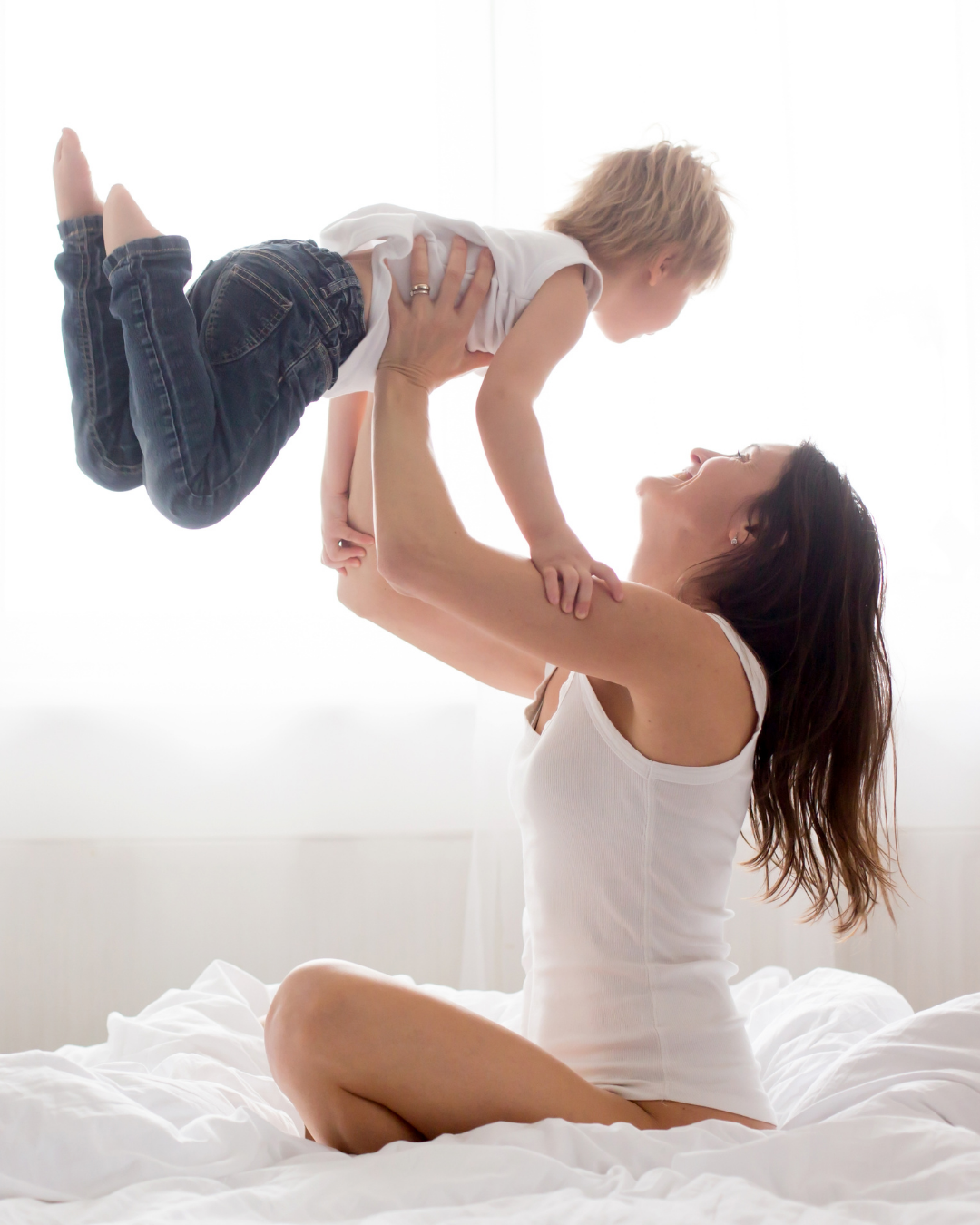 mamá jugando con su hijo en la cama lo lanza hacia arriba